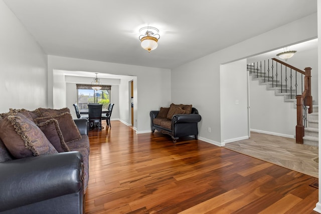 living room with baseboards, wood finished floors, and stairway