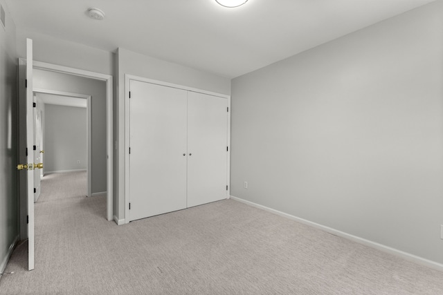 unfurnished bedroom with light colored carpet, baseboards, and a closet