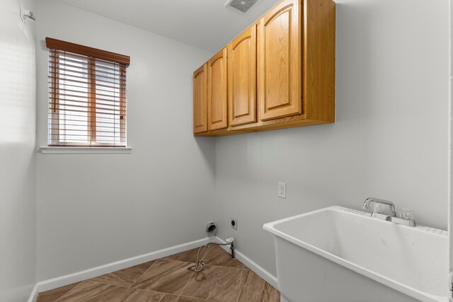 washroom with electric dryer hookup, visible vents, cabinet space, a sink, and baseboards