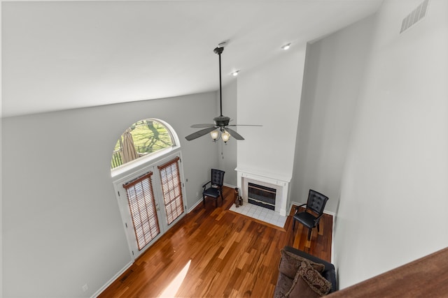 unfurnished living room with a ceiling fan, visible vents, wood finished floors, a tile fireplace, and baseboards