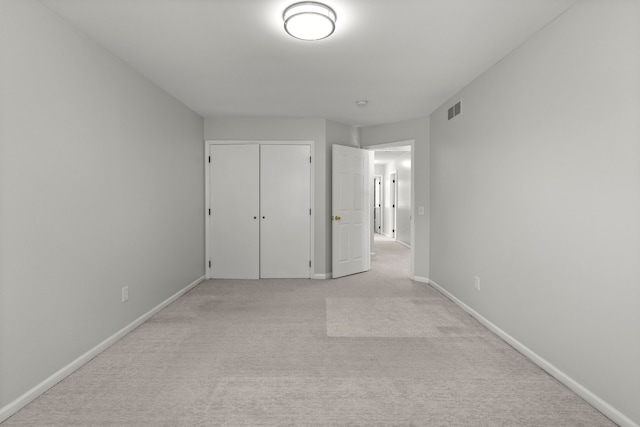 unfurnished bedroom featuring baseboards, visible vents, light carpet, and a closet