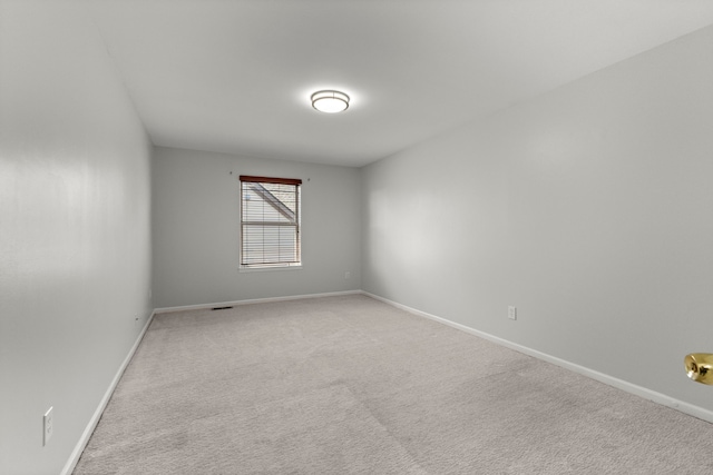 spare room with baseboards and light carpet