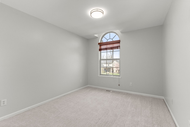 unfurnished room with baseboards, visible vents, and light colored carpet