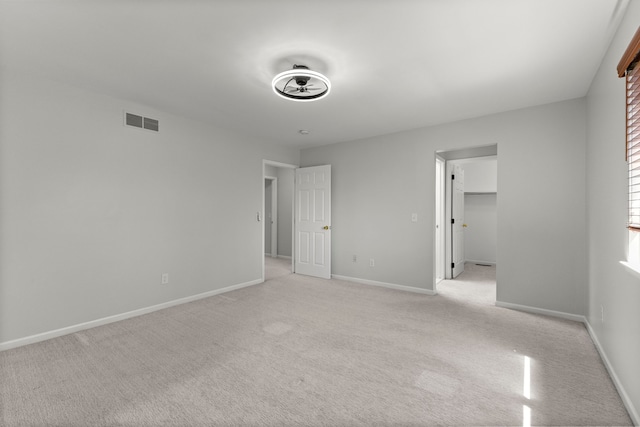 unfurnished bedroom with visible vents, baseboards, a spacious closet, and light carpet