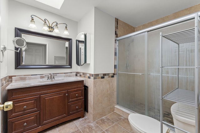 full bathroom featuring vanity, toilet, tile walls, tile patterned floors, and a stall shower