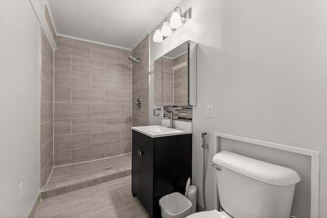 full bathroom featuring vanity, crown molding, toilet, and tiled shower