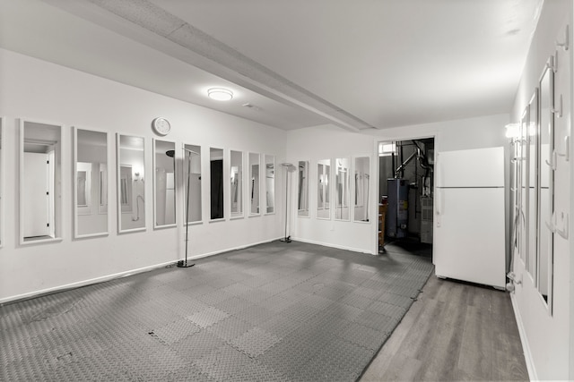 unfurnished room with water heater, baseboards, and dark wood-type flooring