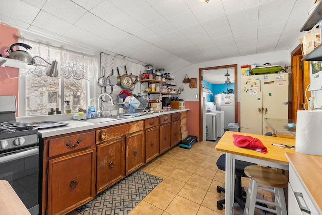 kitchen featuring brown cabinetry, open shelves, light countertops, stainless steel range with gas stovetop, and a sink