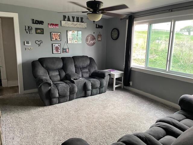 carpeted living room featuring baseboards, plenty of natural light, and a ceiling fan