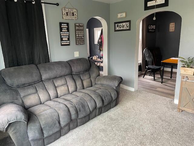 carpeted living area with arched walkways and baseboards