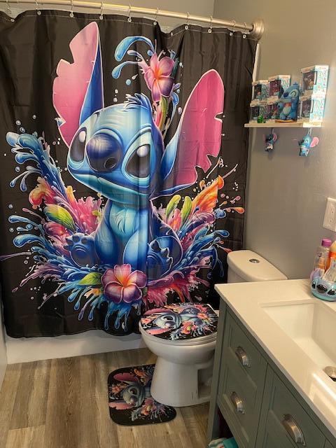 bathroom with vanity, wood finished floors, toilet, and curtained shower