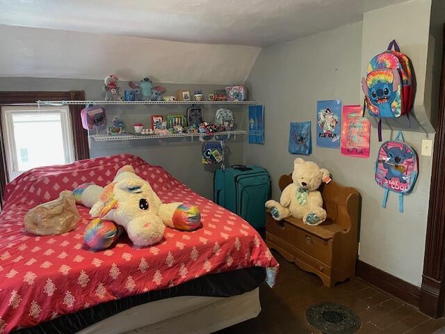 bedroom with baseboards and lofted ceiling