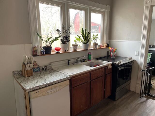kitchen with brown cabinets, light wood finished floors, stainless steel range with electric stovetop, light countertops, and dishwasher