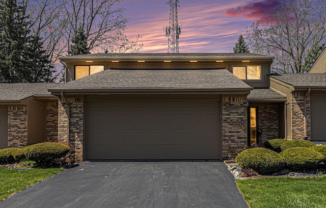 view of front of house featuring an attached garage, brick siding, and aphalt driveway