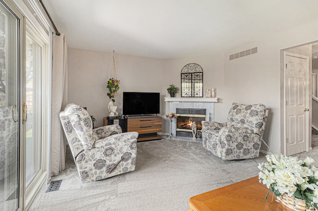 carpeted living area with a wealth of natural light, a premium fireplace, and visible vents