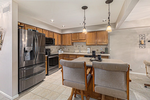 kitchen featuring brown cabinetry, backsplash, visible vents, light countertops, and stainless steel appliances