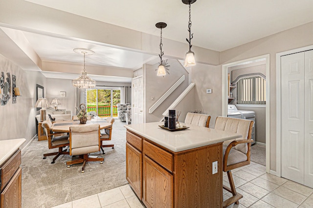kitchen featuring independent washer and dryer, a center island, light tile patterned floors, a kitchen bar, and pendant lighting