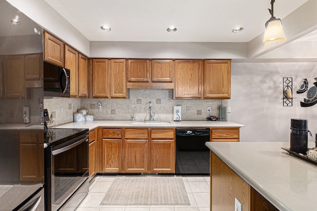 kitchen featuring a sink, decorative backsplash, black appliances, and light countertops