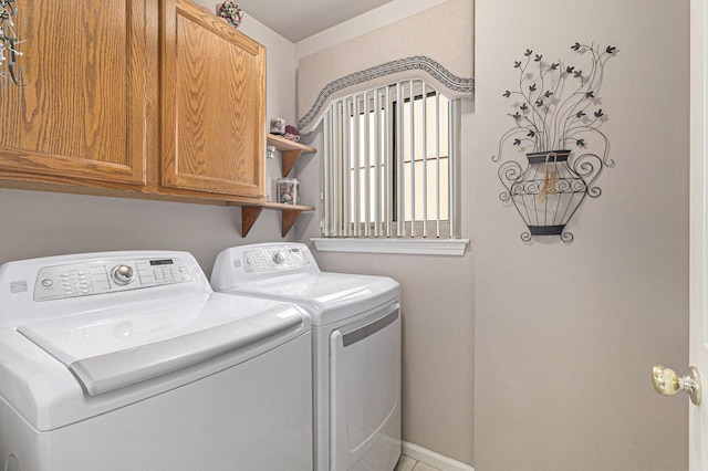 clothes washing area featuring baseboards, cabinet space, and washer and clothes dryer
