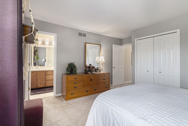 bedroom with visible vents, a closet, light carpet, baseboards, and ensuite bath