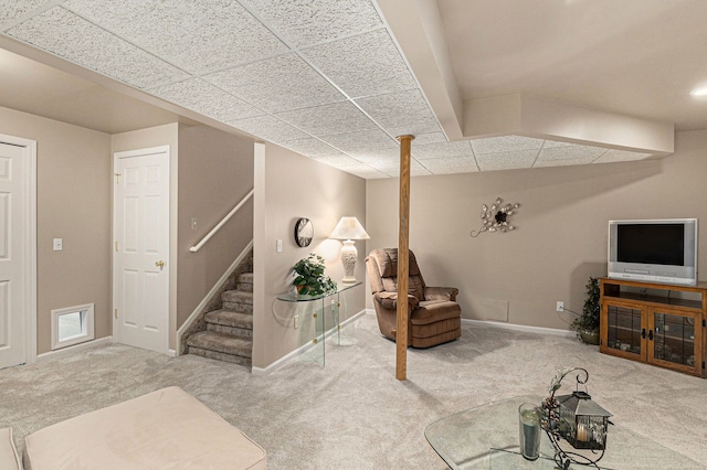 carpeted living area with baseboards, a drop ceiling, and stairway