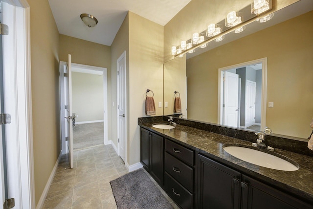 bathroom featuring baseboards, double vanity, tile patterned floors, and a sink