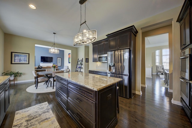 kitchen featuring dark brown cabinetry, light stone countertops, dark wood-style floors, an inviting chandelier, and stainless steel appliances