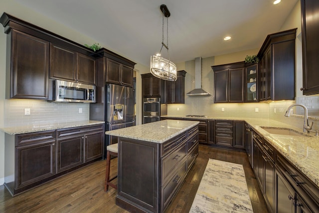 kitchen with backsplash, appliances with stainless steel finishes, a center island, a sink, and wall chimney exhaust hood