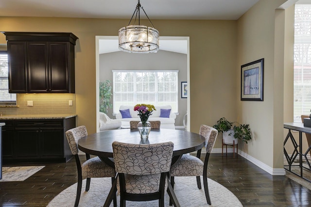 dining area with baseboards, a chandelier, dark wood-style floors, and vaulted ceiling