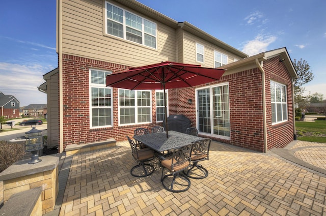 rear view of property with brick siding, outdoor dining area, and a patio area
