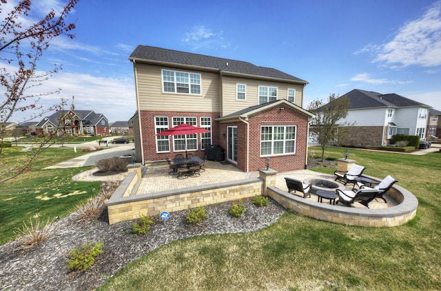 back of house with a yard, a patio, brick siding, and an outdoor fire pit