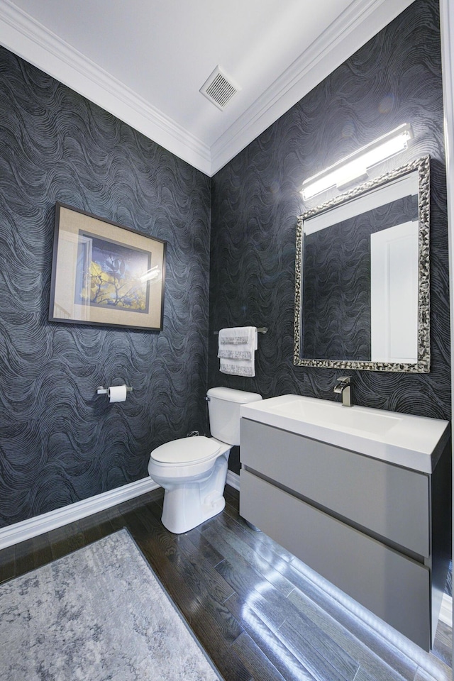 half bathroom with visible vents, ornamental molding, wood finished floors, toilet, and baseboards