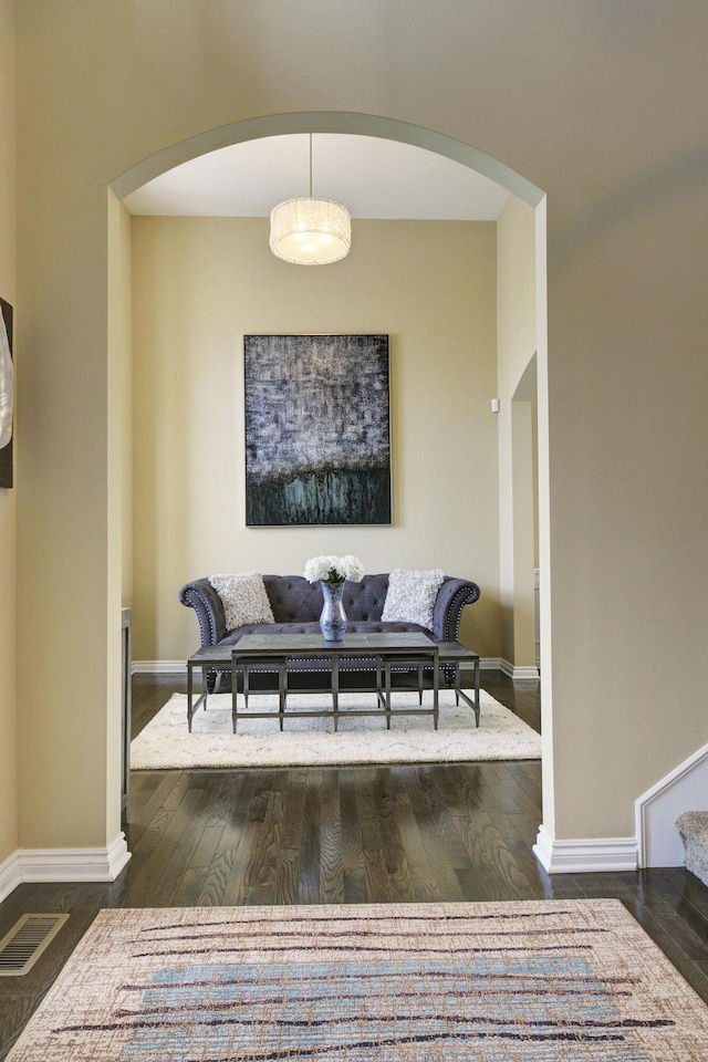living room with arched walkways, baseboards, and wood finished floors
