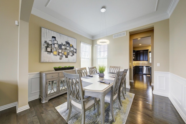 dining room with crown molding, a wainscoted wall, dark wood finished floors, and visible vents