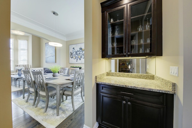 dining space with crown molding, dark wood finished floors, and bar