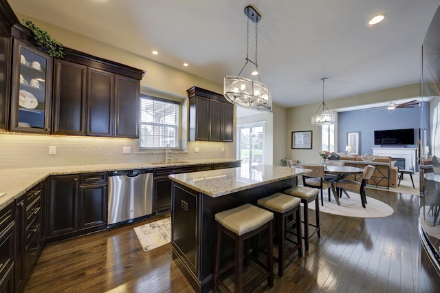 kitchen with decorative backsplash, dark brown cabinetry, dishwasher, dark wood-style floors, and open floor plan