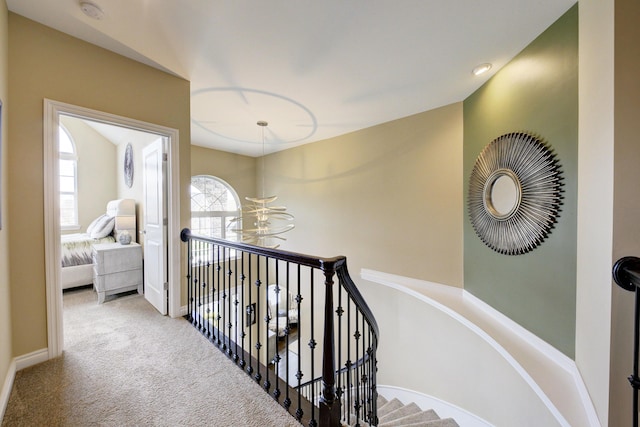 hallway featuring a chandelier, baseboards, an upstairs landing, and carpet