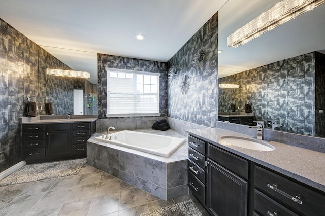 full bath featuring two vanities, a sink, and a bath