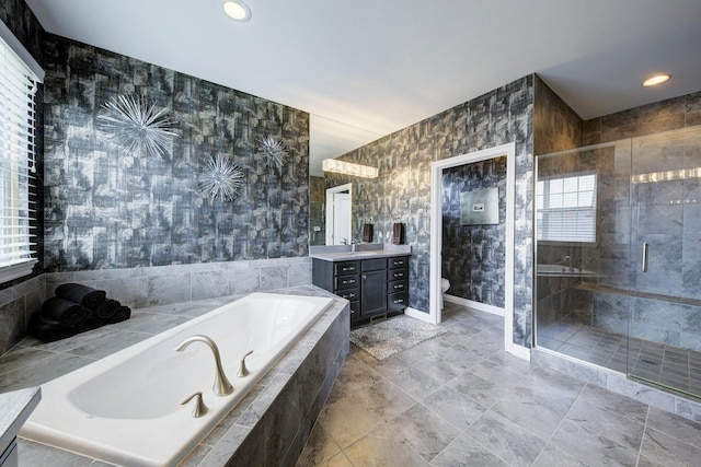 bathroom featuring vanity, a garden tub, toilet, baseboards, and a stall shower