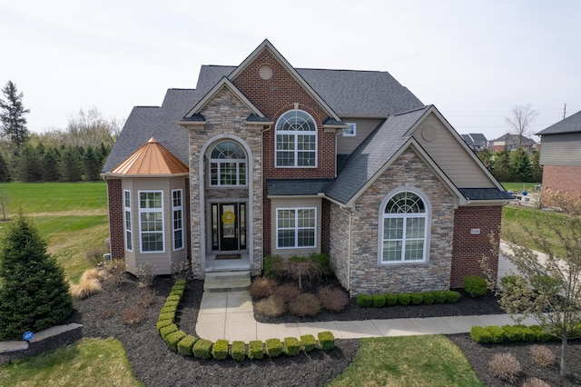 view of front facade with a shingled roof, a front lawn, stone siding, and a standing seam roof
