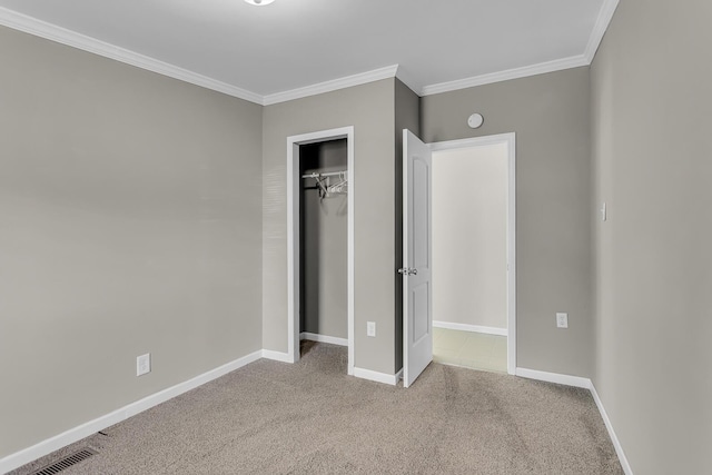 unfurnished bedroom featuring carpet flooring, baseboards, visible vents, ornamental molding, and a closet