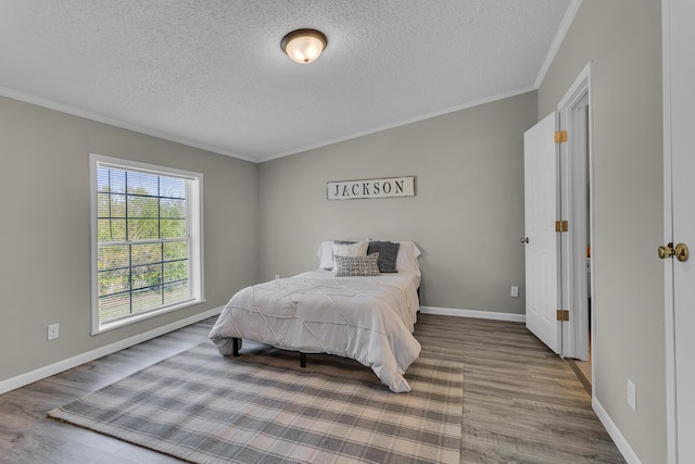 bedroom with crown molding, a textured ceiling, and wood finished floors