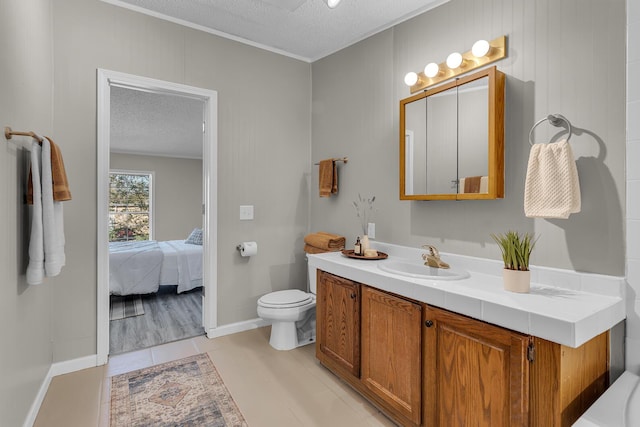 ensuite bathroom with a textured ceiling, tile patterned flooring, vanity, toilet, and ensuite bathroom
