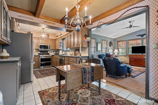 kitchen with a sink, open floor plan, appliances with stainless steel finishes, and light tile patterned floors