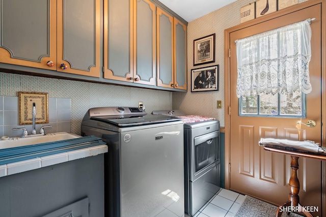 laundry room with cabinet space, separate washer and dryer, wallpapered walls, and light tile patterned floors