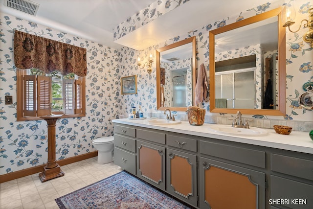 bathroom with visible vents, a sink, baseboards, and wallpapered walls