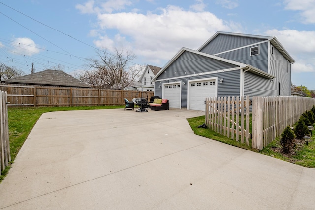 view of side of home featuring an attached garage, concrete driveway, and fence private yard