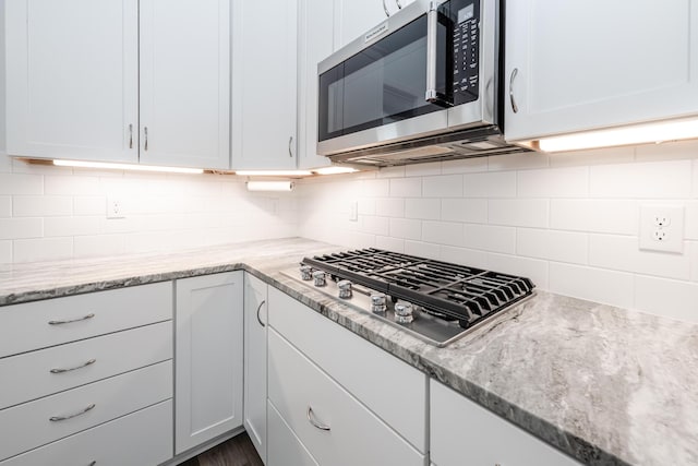 kitchen with white cabinetry, tasteful backsplash, light stone countertops, and stainless steel appliances