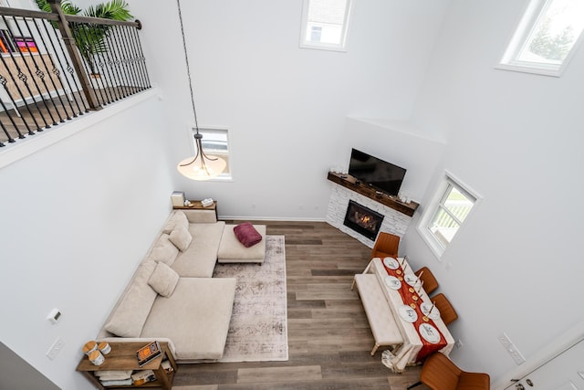 living area featuring stairs, a high ceiling, a glass covered fireplace, and wood finished floors