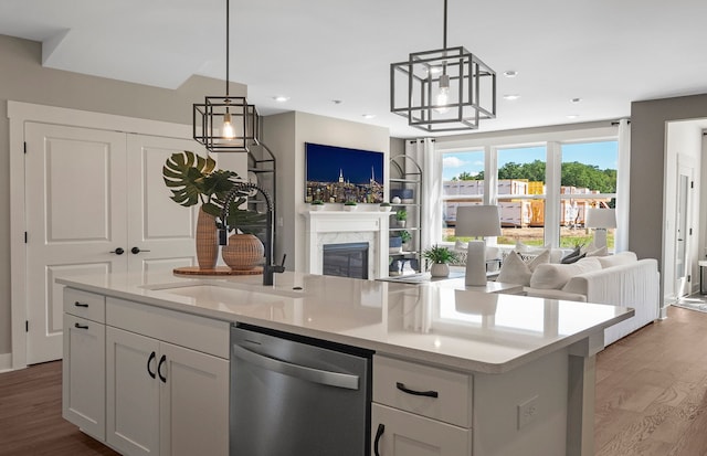 kitchen featuring stainless steel dishwasher, open floor plan, light wood-style flooring, and a premium fireplace
